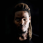 Fetty Wap in a dramatic dark portrait, looking introspective.