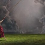 `RAYE pulling a rope against storm clouds, 'This Music May Contain Hope' (2026)`