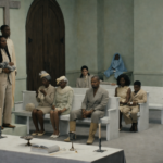 Ye sits in a church pew surrounded by congregation members in cream and white attire in the 'Father' music video