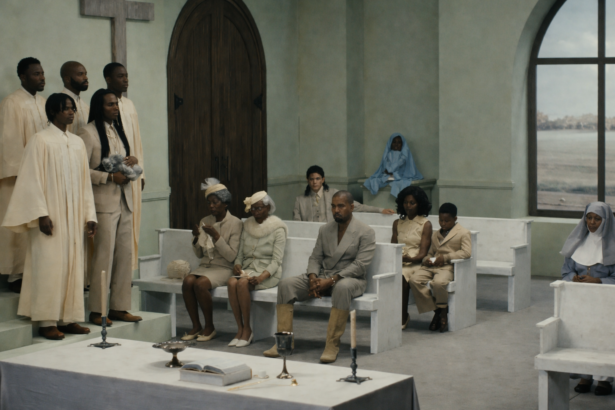 Ye sits in a church pew surrounded by congregation members in cream and white attire in the 'Father' music video