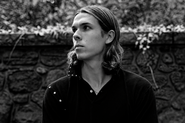 Black and white portrait of Loukeman against a stone wall.