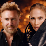 David Guetta and Jennifer Lopez pose together against a warm golden bokeh background, both dressed in black, for their collaborative single Save Me Tonight