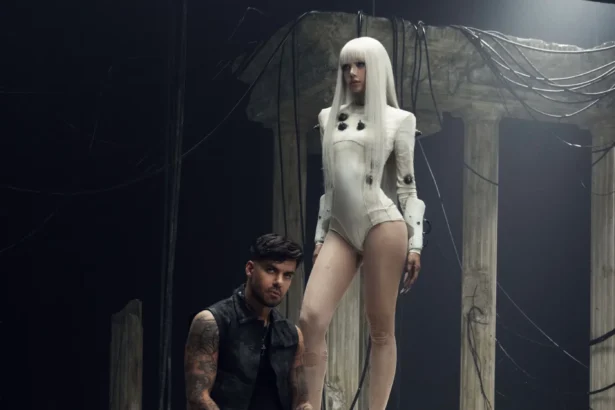 Futuristic scene from Bad Angel LISA stands in an ivory bodysuit above Anyma, set among ruined pillars and tangled cables, blending ancient and cyberpunk aesthetics.