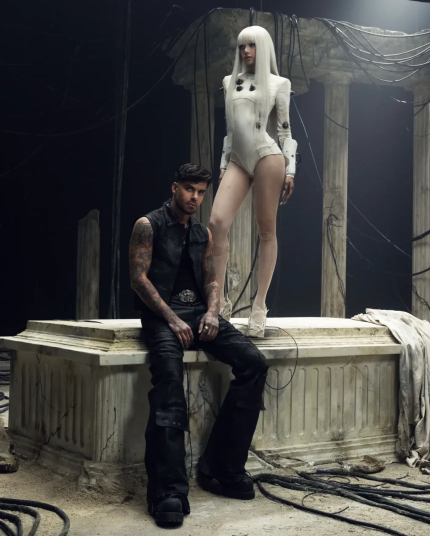 Futuristic scene from Bad Angel LISA stands in an ivory bodysuit above Anyma, set among ruined pillars and tangled cables, blending ancient and cyberpunk aesthetics.