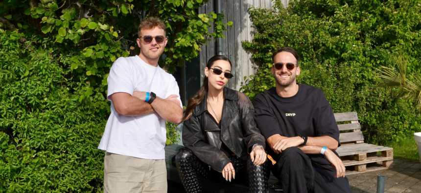 Lauren Mia and MAMI photographed together at a festival, the trio posing in front of a lush green wall
