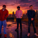Short Alt Text (SEO-optimized): Legacy III Singapore R&B trio posing on a rooftop at sunset with a city skyline in the background