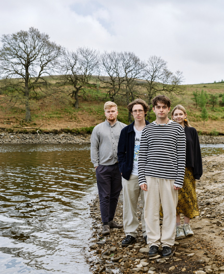 Manchester indie four-piece pyncher standing on a rocky riverbank surrounded by bare trees and rolling hills