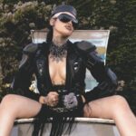 Nxdia in a bold black leather look and sunglasses, posing confidently outdoors, capturing the dark, rebellious mood of Lovemesick.