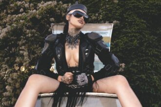 Nxdia in a bold black leather look and sunglasses, posing confidently outdoors, capturing the dark, rebellious mood of Lovemesick.