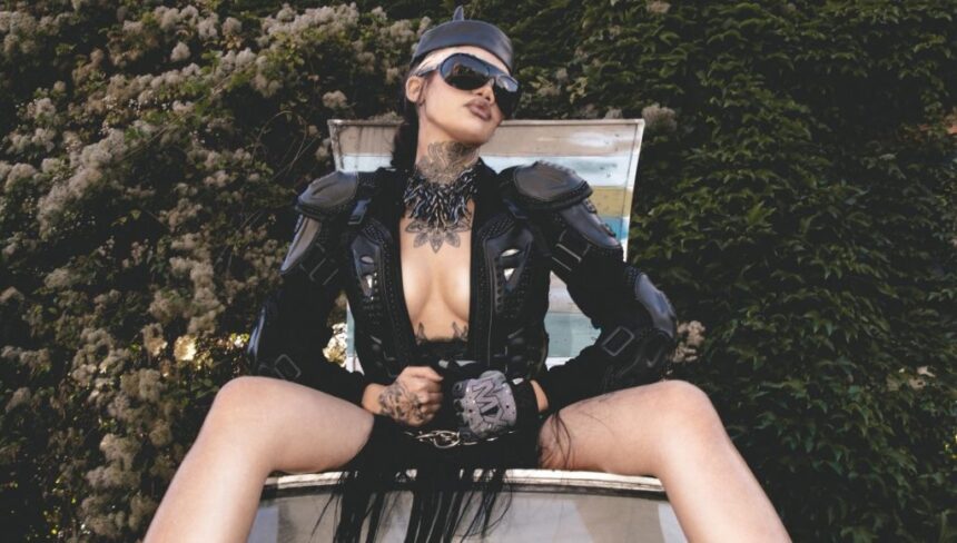 Nxdia in a bold black leather look and sunglasses, posing confidently outdoors, capturing the dark, rebellious mood of Lovemesick.