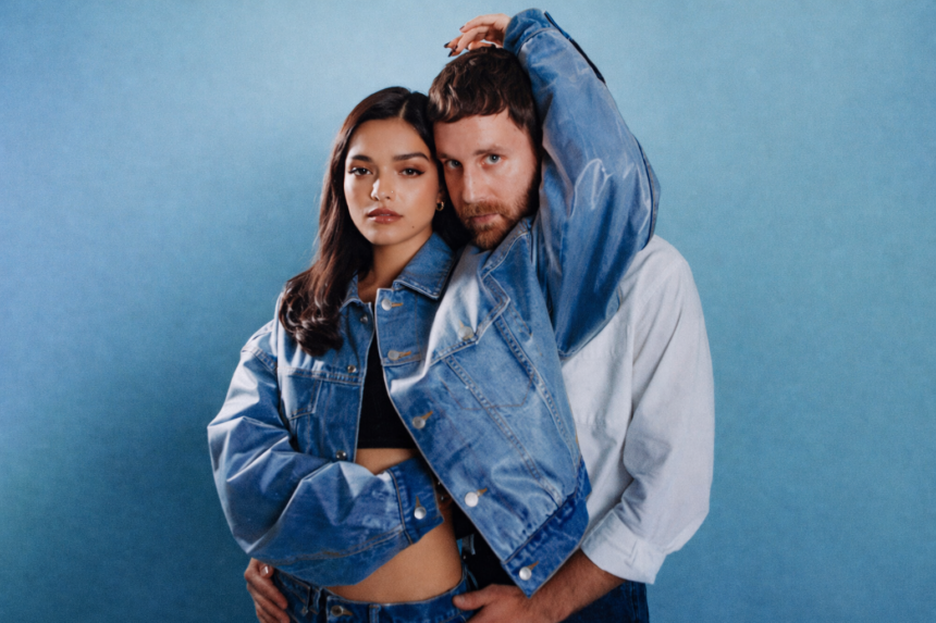 Rachel Zegler and Ben Platt pose together in matching denim jackets against a blue background for The Last Five Years 25th Anniversary live album press photo