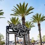 Rolling Loud festival sign surrounded by palm trees under a clear blue sky