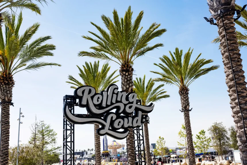 Rolling Loud festival sign surrounded by palm trees under a clear blue sky