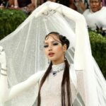 Lisa attends the Met Gala 2026 in a sparkling white couture gown with long gloves and a dramatic crystal veil, posing on the red carpet in an avant-garde fashion look.
