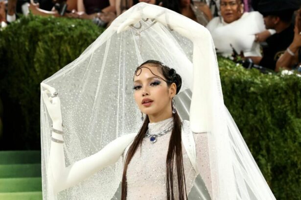 Lisa attends the Met Gala 2026 in a sparkling white couture gown with long gloves and a dramatic crystal veil, posing on the red carpet in an avant-garde fashion look.