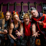 Chatrooms band posing in front of a wall of electric guitars, wearing casual rock outfits, with four members striking energetic poses.