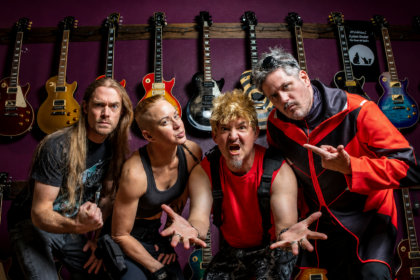 Chatrooms band posing in front of a wall of electric guitars, wearing casual rock outfits, with four members striking energetic poses.