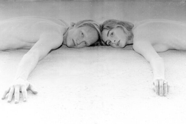 Dancing In Tongues press photo — black and white image of two people lying side by side, heads touching, arms extended, looking directly into the camera