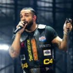 Drake performing live at Wireless Festival London 2025 wearing a black leather patch vest on stage with microphone