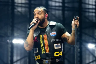 Drake performing live at Wireless Festival London 2025 wearing a black leather patch vest on stage with microphone