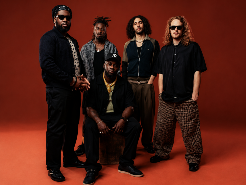 Ezra Collective five-piece band in a 2026 press photo against a red background
