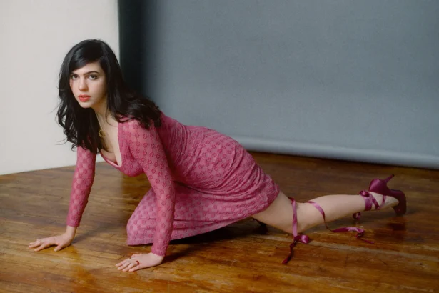 Julia Cumming in a pink lace mini dress, posing on a hardwood floor. Photo by Marcus Maddox