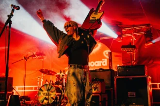 `Keo's Finn Keogh raises his guitar triumphantly on the Billboard U.K. stage at The Great Escape Festival 2026 in Brighton.`