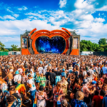 `Crowds fill the main stage arena at Love Saves The Day festival in Bristol, with the iconic heart-shaped orange stage structure under a bright summer sky.`
