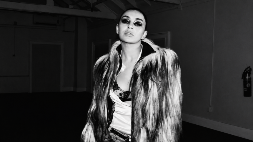 Promotional cover image for Perfect featuring Yella Yella in a black-and-white fashion-style portrait, wearing a dramatic fur coat with bold eye makeup in a dimly lit industrial setting.