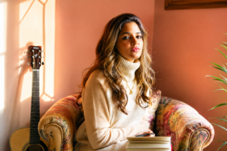 Official single artwork for Tasha Keswani's 'Hello Stranger Hello,' featuring the Bangalore singer-songwriter seated on a vintage sofa with a guitar in the background.`
