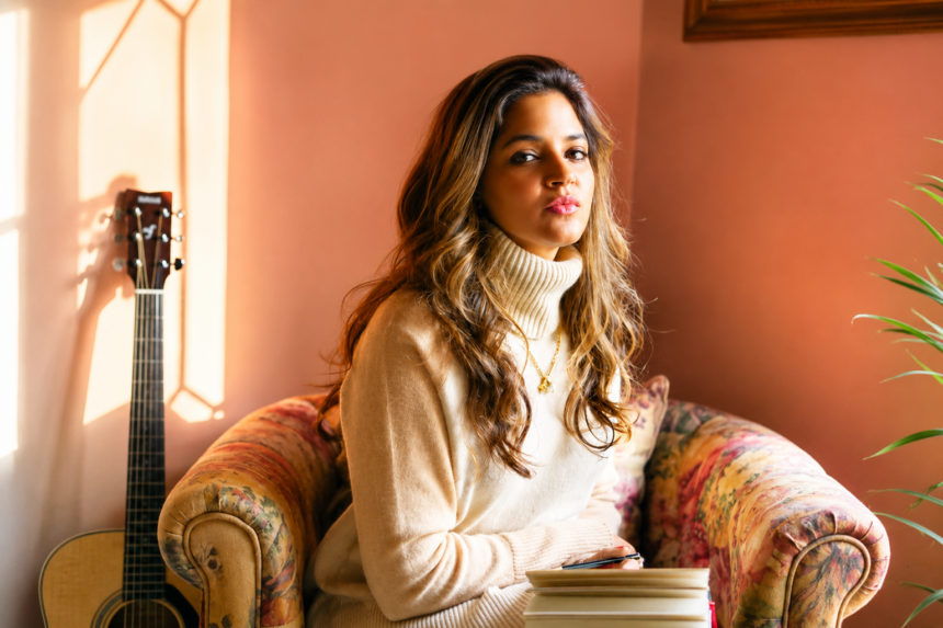 Official single artwork for Tasha Keswani's 'Hello Stranger Hello,' featuring the Bangalore singer-songwriter seated on a vintage sofa with a guitar in the background.`