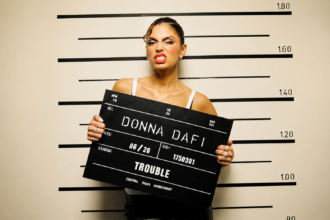 Donna Dafi official press photo for Trouble single Record17 2026 styled as mugshot police lineup themed cover art