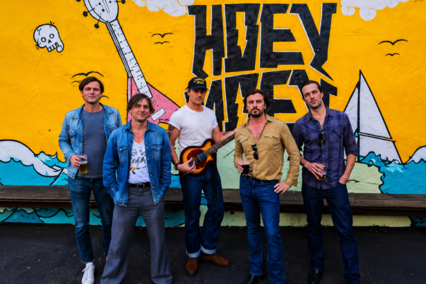 Jet band posing in front of a colorful mural in Melbourne, Australia, with five members standing casually outdoors