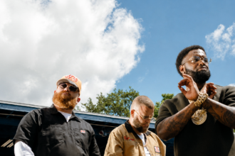 Sam E Hues and Nino Breeze pose beside a classic car in a bold outdoor shot promoting their Gulf Coast anthem, "Chrome."