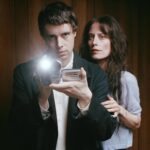 Boy Harsher's Augustus Muller and Jae Matthews pose with a vintage camcorder for their album Get Mean