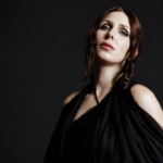 Chelsea Wolfe photographed in black draped fabric against a dark background for her album The Dark