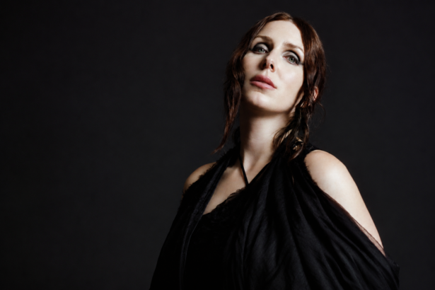 Chelsea Wolfe photographed in black draped fabric against a dark background for her album The Dark