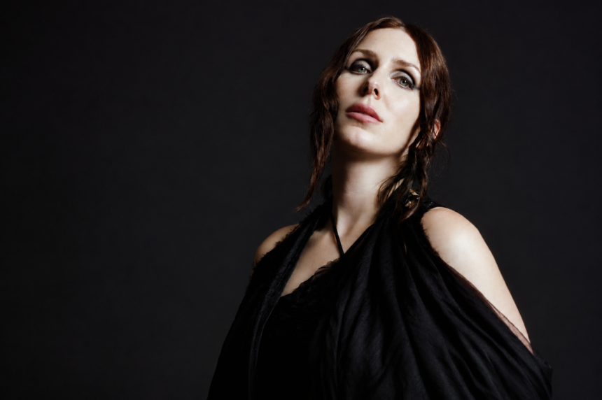Chelsea Wolfe photographed in black draped fabric against a dark background for her album The Dark