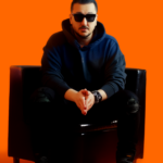 Daijo wearing a dark hoodie and sunglasses while seated in a black armchair against a vibrant orange background