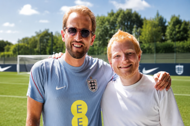 Ed Sheeran and Harry Kane smiling with arms around each other on an England training pitch