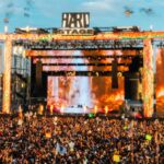 Massive crowd gathered at the HARD Stage during HARD Summer Music Festival, with pyrotechnics and giant LED screens lighting up the main stage at sunset