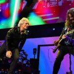 Jon Bon Jovi and guitarist Phil X perform onstage under colored lights during a Bon Jovi concert