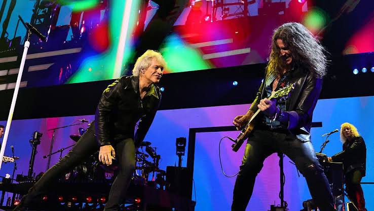 Jon Bon Jovi and guitarist Phil X perform onstage under colored lights during a Bon Jovi concert