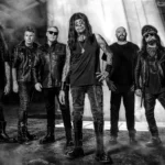 Ministry photographed in black and white in an industrial space, frontman Al Jourgensen at center in a warehouse haze