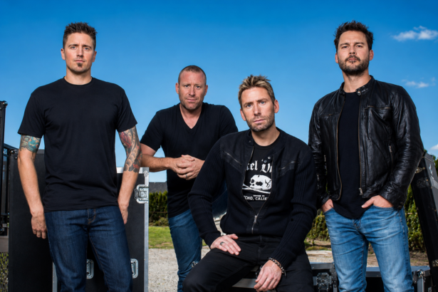 Nickelback band members Ryan Peake, Mike Kroeger, Chad Kroeger and Daniel Adair posing outdoors in black outfits beside road cases, promoting their new album Everything Under The Sun