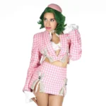 Slay Raché poses in a pink houndstooth suit and green wig against a white background