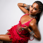 Tyla poses in a red fringed outfit and silver jewelry against a white backdrop for her album A*POP
