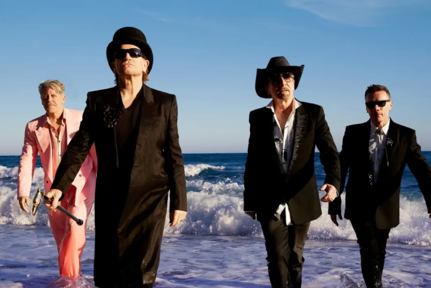 U2 members Bono, The Edge, Adam Clayton, and Larry Mullen Jr. walk out of the ocean in suits and hats in the promotional photo for their new single 'Street of Dreams.'