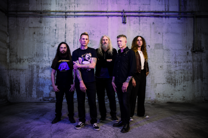 The five members of Mastodon stand against a concrete wall in dark clothing, in press art for their ninth album 'Marrow Deep.'