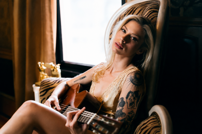 Andie Case, whose single 'Better Days' previews her debut EP, holds an acoustic guitar in a warmly lit portrait.